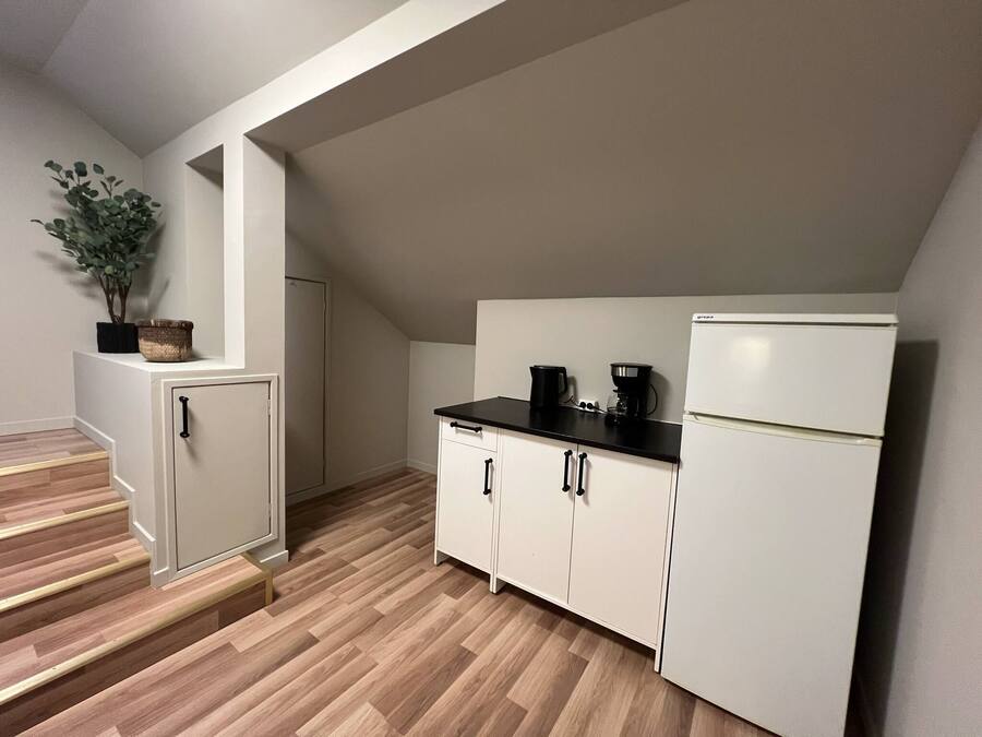 A compact kitchen with a refrigerator, stove, and cabinets.