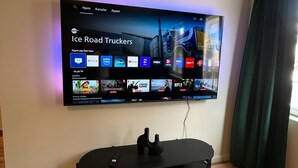 Televisor de pantalla plana montado en la pared, mostrando la interfaz de un servicio de streaming con diversas opciones de contenido.