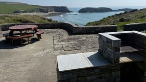 An outdoor seating area with a stone bench and picnic table overlooking a coastal landscape. - The Granary Loft at Annestown House (Annestown)