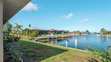 Un quartier résidentiel avec un canal, des maisons et un quai où est amarré un bateau.