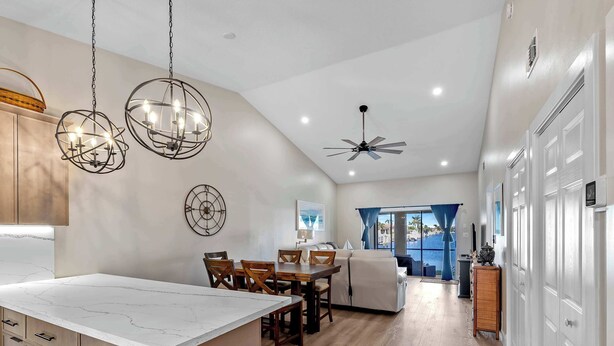 A modern kitchen with a marble countertop, wooden cabinets, and pendant lighting. - Punta Gorda Isles Villa On The Waterfront (Punta Gorda)