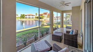 A balcony with a view of a body of water, wicker furniture, and a ceiling fan. - Punta Gorda Isles Villa On The Waterfront (Punta Gorda)