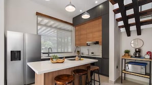 A modern kitchen with a central island, stainless steel appliances, wooden cabinets, and a window providing natural light.