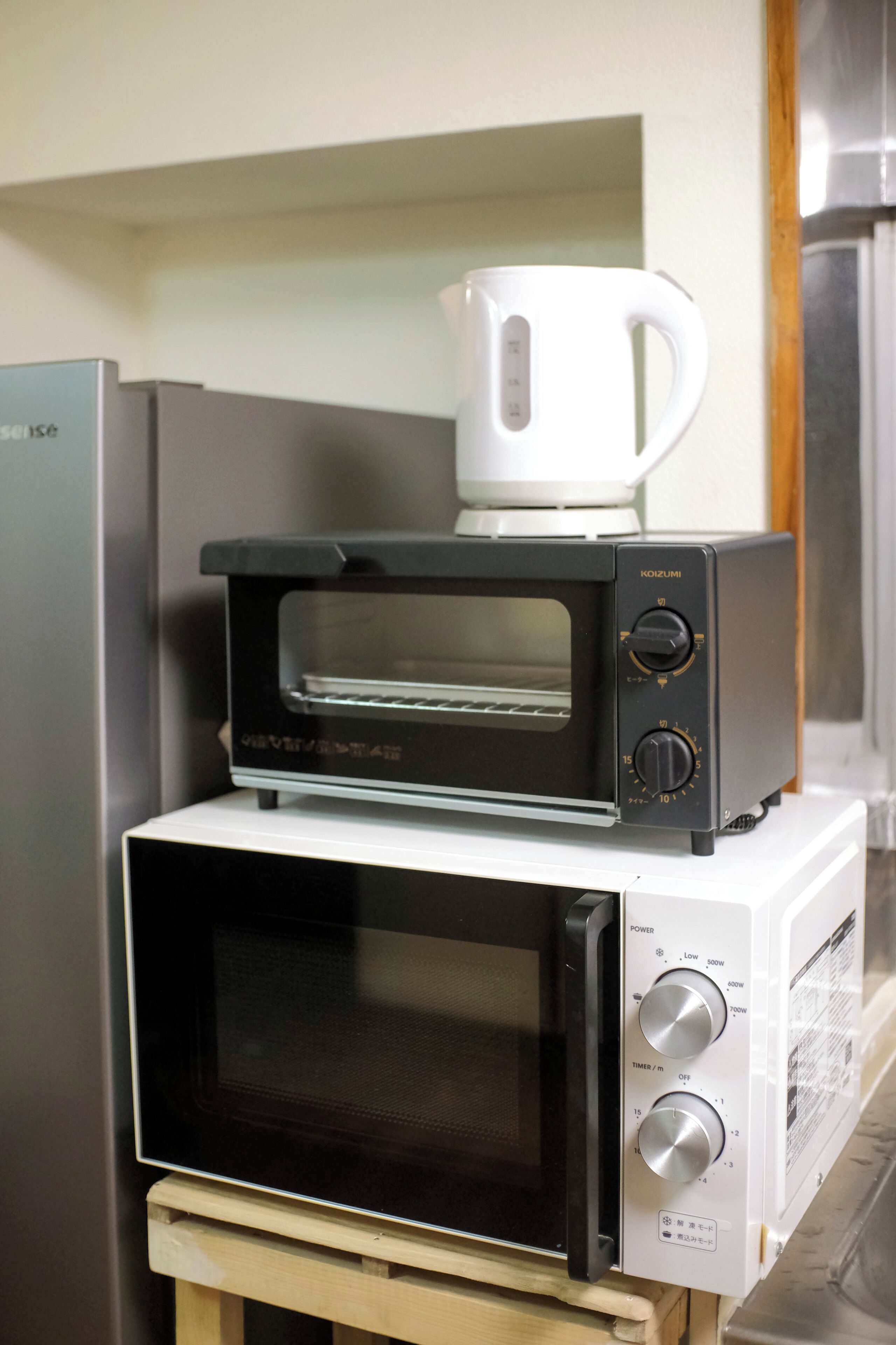 Una cucina con microonde, tostapane e macchina del caffè uno sopra l'altro.