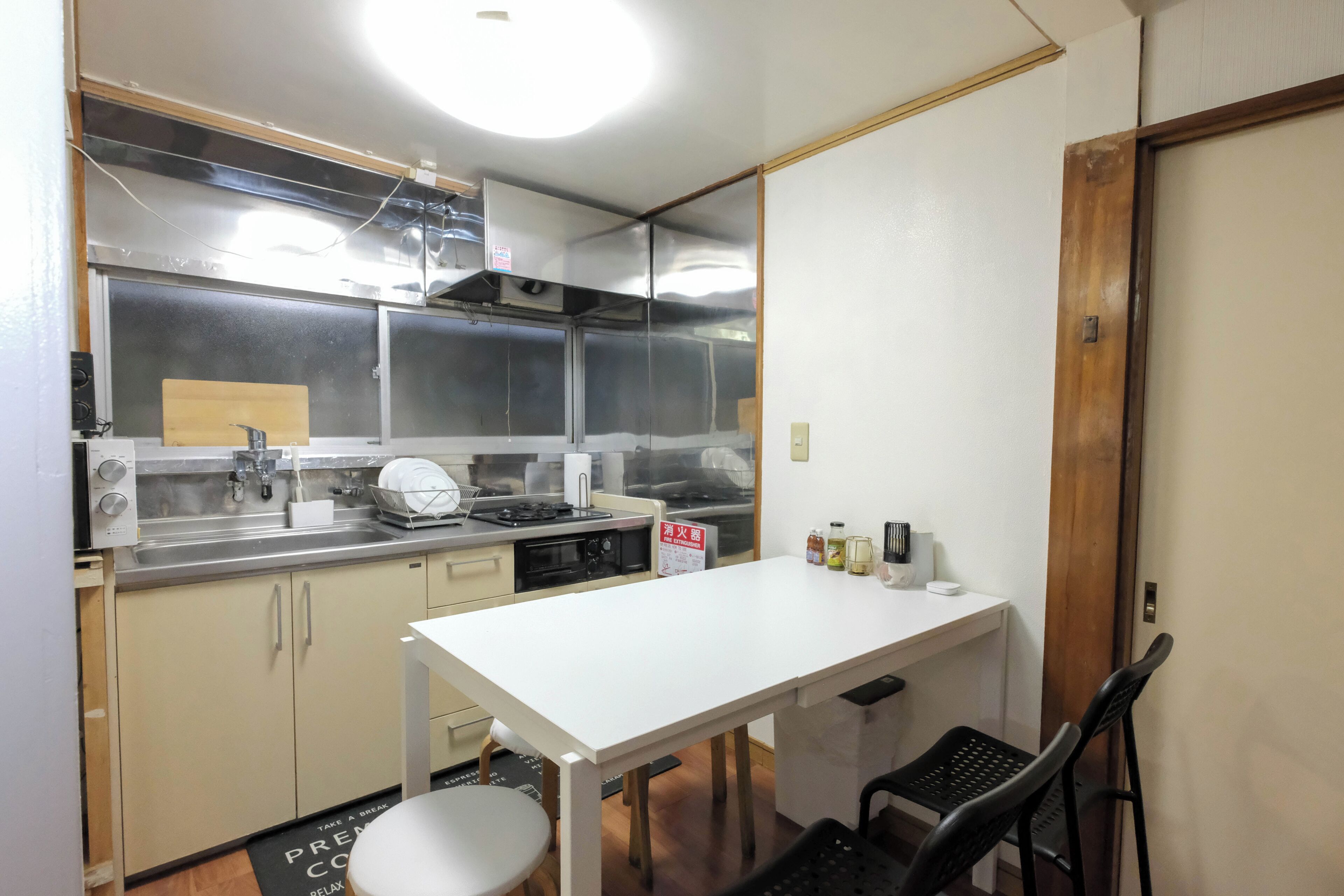 A compact kitchen with a white countertop, stainless steel appliances, and a small dining area with a table and chairs.