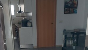 A modern kitchen with white appliances, a wooden door, and a dining area with a patterned rug. - ELITE apartment 200 meters from the beach (Cullera)
