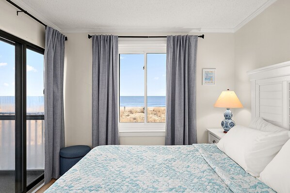 A bedroom with a bed, a nightstand, a lamp, and a window with curtains.