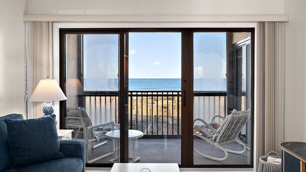 A hotel room with a balcony, a sofa, a table, and a chair. - Oceanfront 2 Bed/2 Bath, Sleeps 8 (Ocean City)