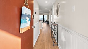 A hallway with a wooden floor, white walls, and a door with a 'Welcome' sign. - Oceanfront 2 Bed/2 Bath, Sleeps 8 (Ocean City)