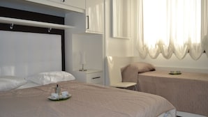 Ein modernes Schlafzimmer mit einem großen Bett, einem Nachttisch, einem Stuhl und einem kleinen Tisch mit Tassen und Tellern.