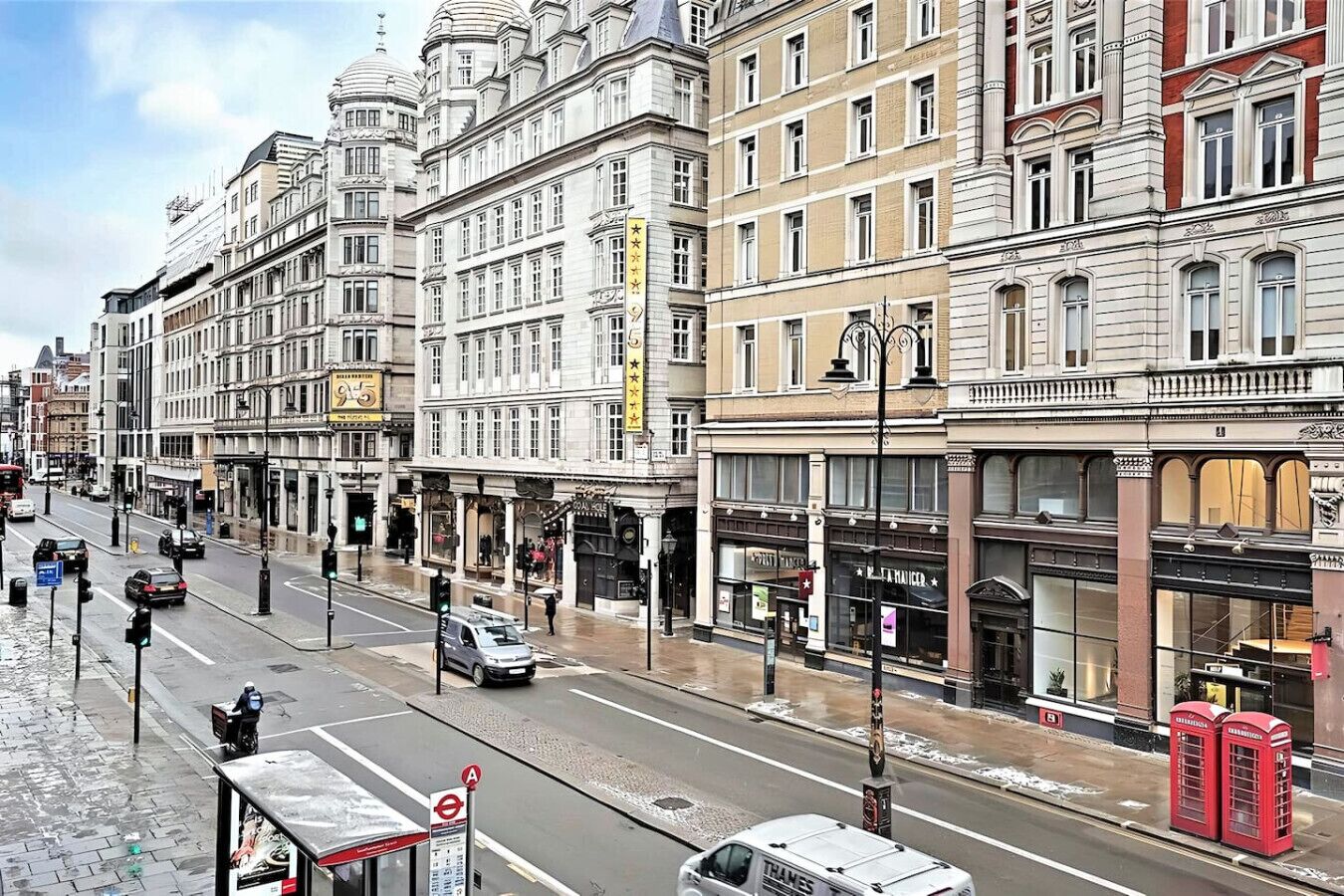 A street view with buildings, a bus stop, and a red telephone booth.
