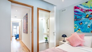A modern bedroom with a bed, a nightstand, a lamp, and a painting on the wall.