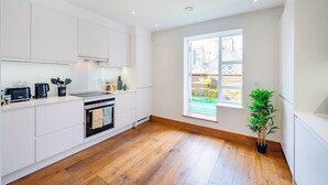 A modern kitchen with white cabinets, a black stove, and a wooden floor.