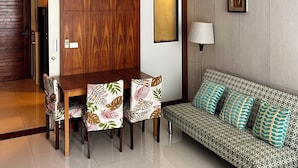 A modern living room with a wooden dining table, patterned sofa, and a framed picture on the wall. - Apartment with garden view (Tambon Karon)