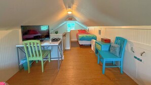 Une petite chambre mansardée, chaleureuse et accueillante, avec un bureau, une chaise et un lit.
