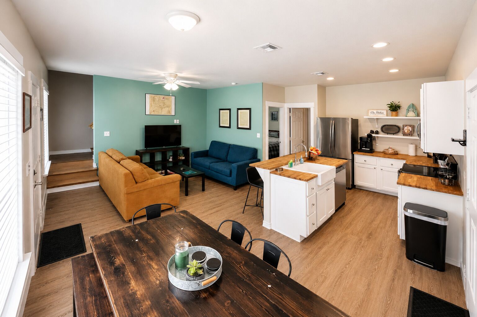 Un espace de vie compact comprenant un coin repas, une kitchenette et un canapé bleu.