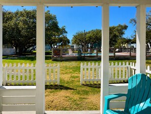 Un espace extérieur abrité, agrémenté d’une clôture en bois peinte en blanc, d’une piscine et de chaises.