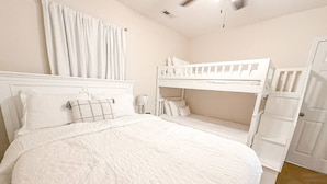A bedroom with a large bed, two bunk beds, a wardrobe, and a curtain. - Lakefront Luxury 2BD/2BA Condo at The Falls-7PP (Lake Ozark)