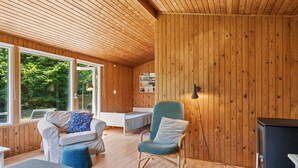 Un interior de cabaña acogedor con paredes de madera, un sofá, una silla y una cama.