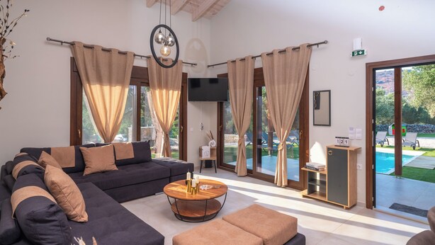 A modern living room with a sectional sofa, a round coffee table, and a view of an outdoor swimming pool.