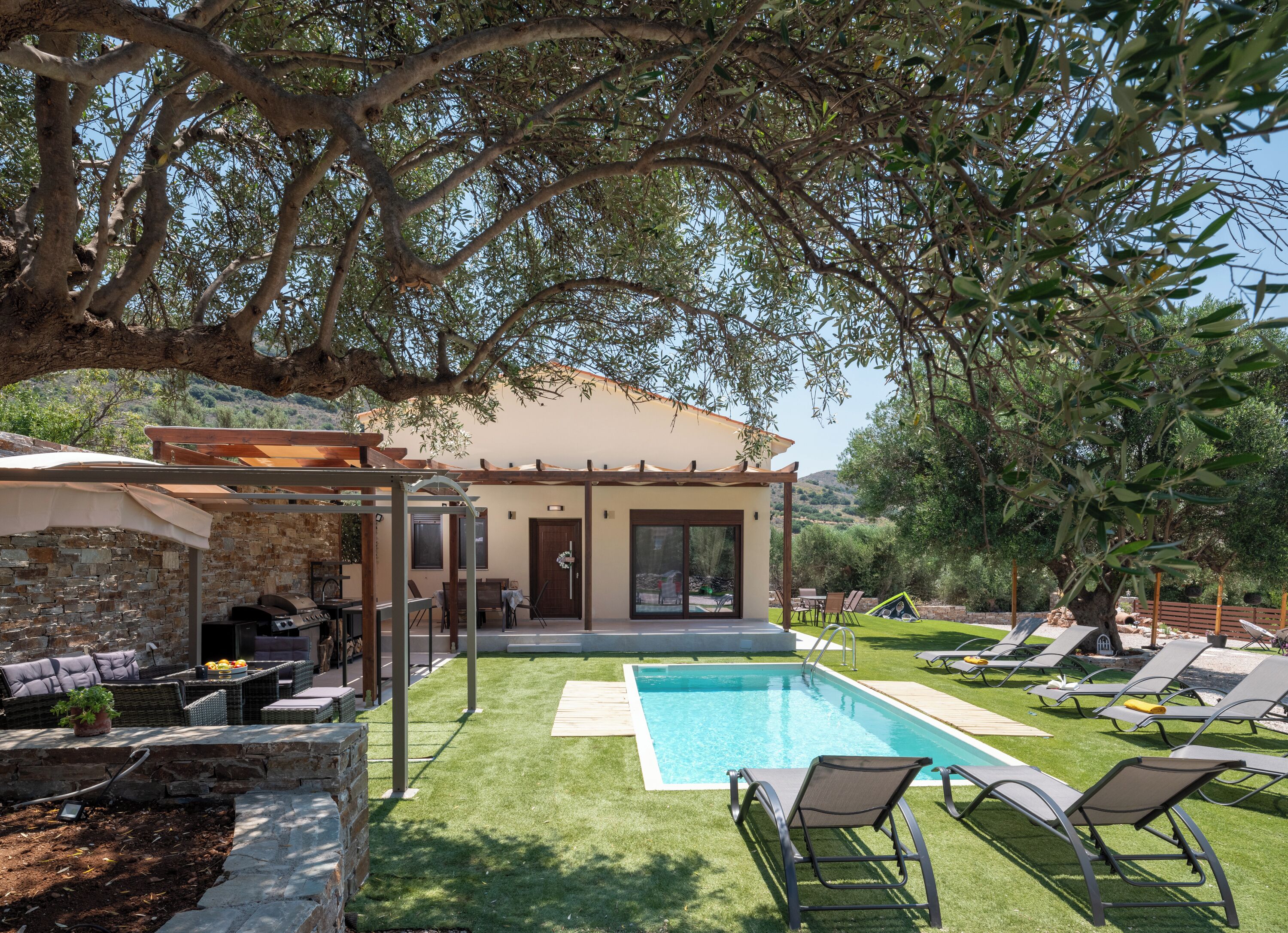 Una villa moderna con piscina, area relax all'aperto e un pergolato.