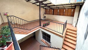 Une terrasse extérieure à plusieurs niveaux, agrémentée d’une pergola en bois, d’un petit coin salon et d’un escalier.