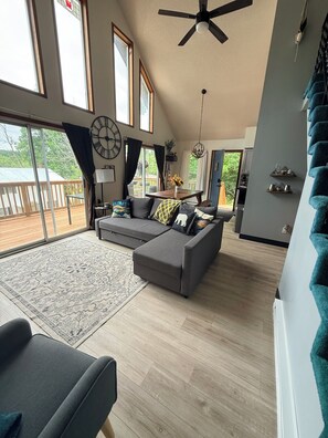 A spacious living room with a large gray sectional sofa, a wooden floor, and a ceiling fan.