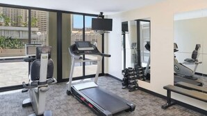 Gimnasio de hotel con cinta de correr, bicicleta estática y pesas.