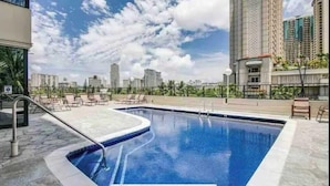 Una piscina en la azotea con sillas de descanso y vistas panorámicas de la ciudad.