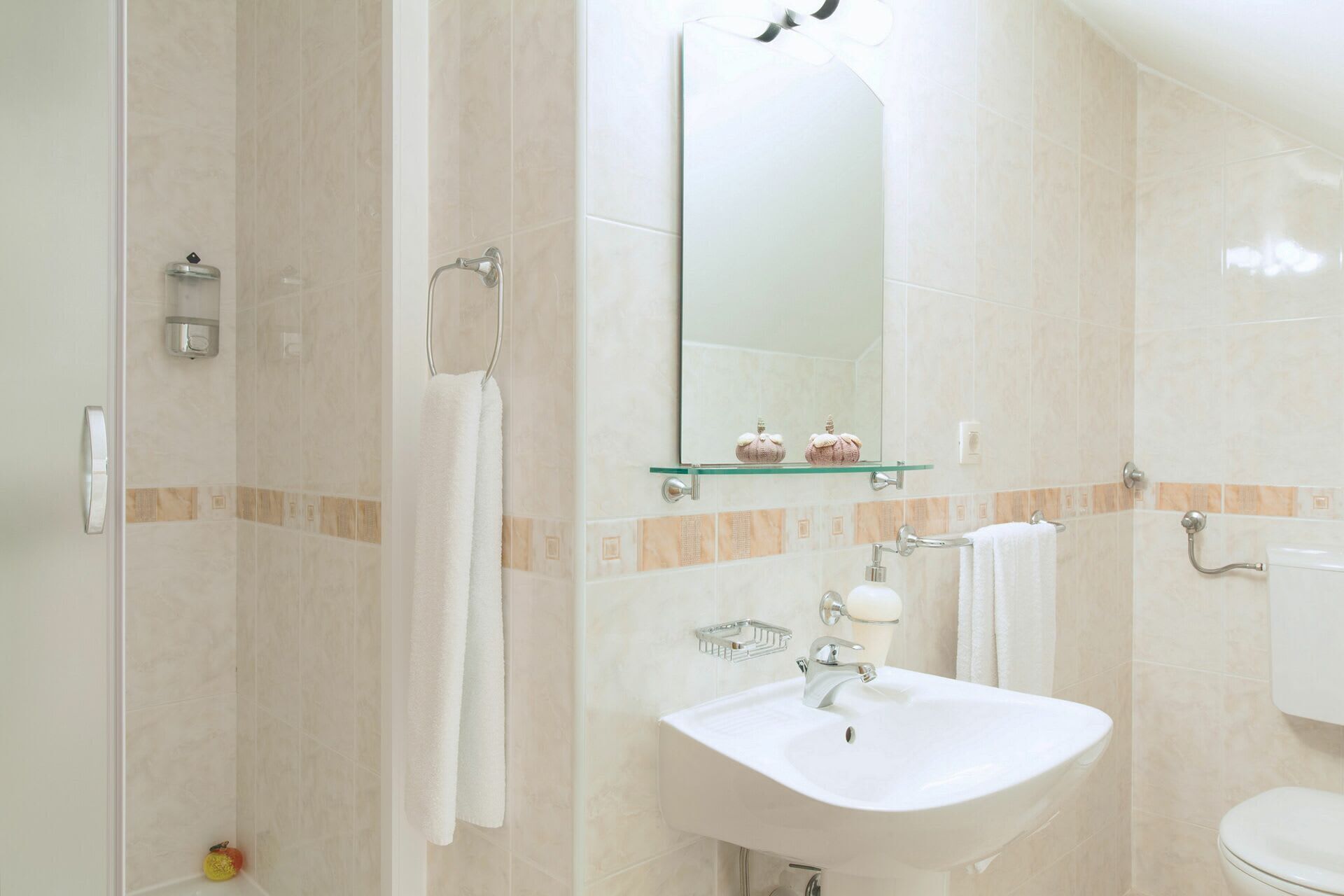 A bathroom with a shower, sink, toilet, and a mirror.