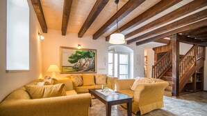 A cozy living room with a wooden ceiling, a painting of a tree, a sofa, a chair, and a staircase. - Villa Ivana Summary: (Mirca)