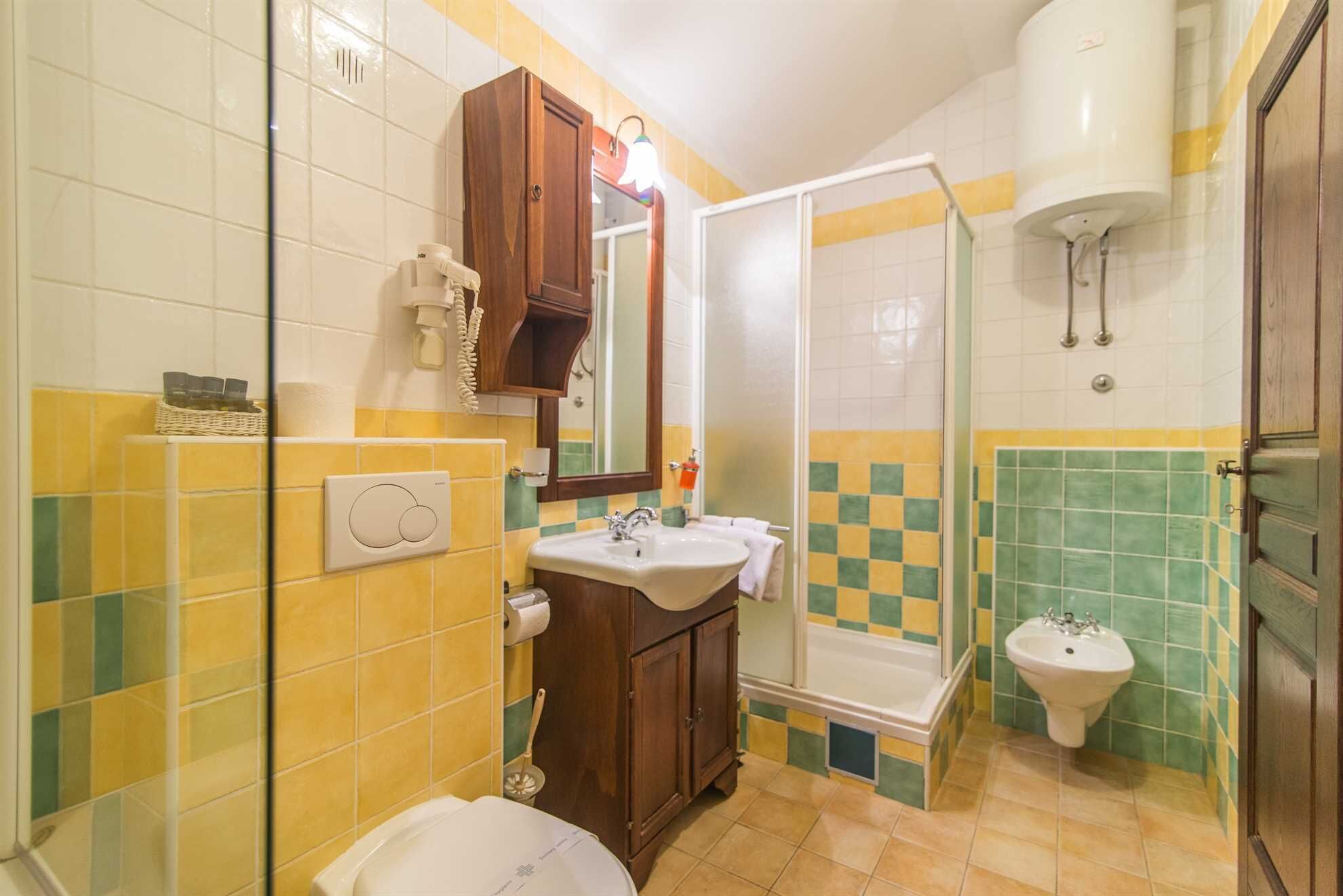 A bathroom with a shower, toilet, sink, and a mirror.