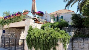 A stone building with a balcony adorned with potted plants, a metal gate, and a clear sky. - Villa Ivana Summary: (Mirca)