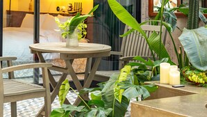 Une table ronde en bois, entourée de chaises, et agrémentée de plantes verdoyantes et d’un vase rempli de fleurs.