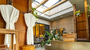 Un hall d’hôtel doté d’un sol à motifs géométriques, de meubles en bois et d’un comptoir d’accueil.