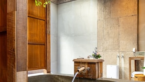 Une salle de bain moderne avec une grande baignoire, des meubles en bois et un mur en pierre.