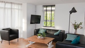 Una sala de estar moderna con un sofá de cuero negro, una mesa de centro de madera y una lámpara de pie negra.