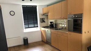 Cocina compacta con armarios de madera, lavavajillas, estufa y lavabo.