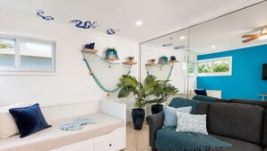 Ein modernes Wohnzimmer mit einem weißen Sofa, einem dunkelgrauen Couchen und einer großen Topfpflanze.