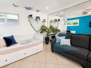 A modern living room with a white sofa, a dark grey couch, and a large potted plant.