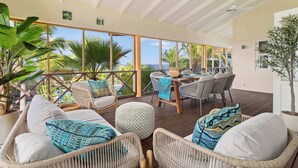 A spacious outdoor seating area with wicker furniture, a wooden table, and a view of the ocean. - Villa Happy Turtle with a spectacular ocean view (Kralendijk)