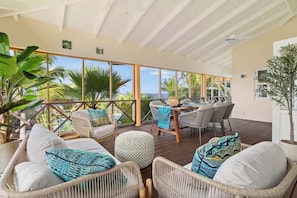 A spacious outdoor seating area with wicker furniture, a wooden table, and a view of the ocean. - Villa Happy Turtle with a spectacular ocean view (Kralendijk)