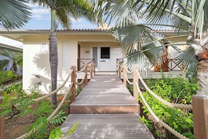 A wooden pathway leading to a building with a white facade and a door. - Villa Happy Turtle with a spectacular ocean view (Kralendijk)