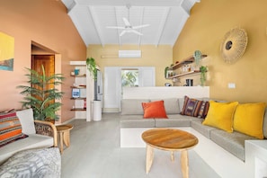 A modern living room with a grey sofa, a wooden coffee table, and a white ceiling fan.