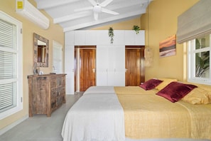 A bedroom with a bed, a dresser, a ceiling fan, and a window with blinds. - Villa Happy Turtle with a spectacular ocean view (Kralendijk)