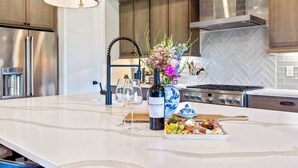 Een keuken met een marmeren eiland, roestvrijstalen apparatuur en een backsplash van mozaïek tegels in een visgraatpatroon.