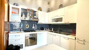 Une cuisine moderne avec des meubles blancs, un dosseret en carreaux noirs et un îlot central.