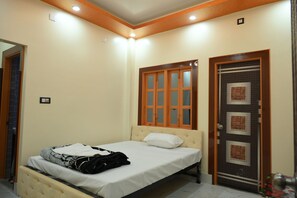 A bedroom with a bed, a wardrobe, and a door with a window. - Blessing Resort (Kalna)