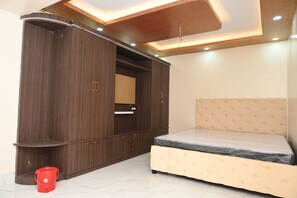 A bedroom with a bed, wardrobe, and a red bucket on the floor. - Blessing Resort (Kalna)