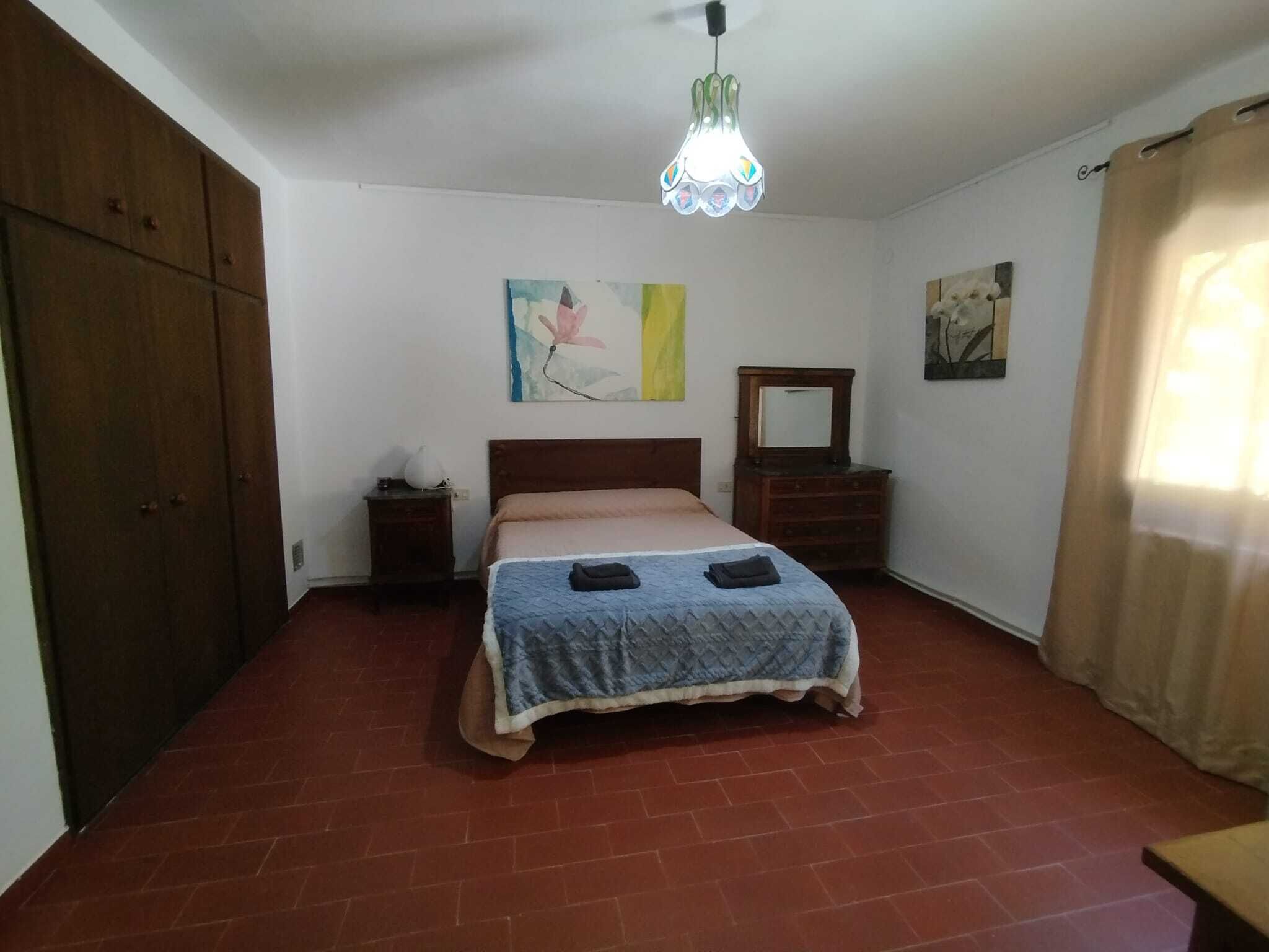 Una camera da letto con un letto, una cassettiera, un comodino e un lampadario.
